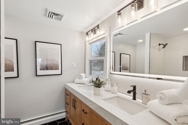 bathroom with tiled shower, baseboard heating, and vanity