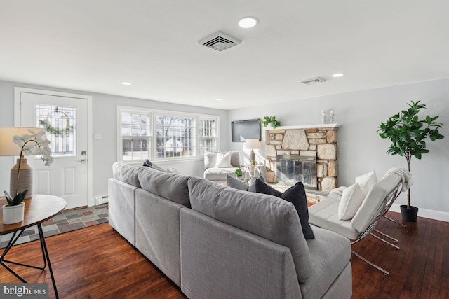 living room featuring dark hardwood / wood-style flooring, a stone fireplace, and baseboard heating