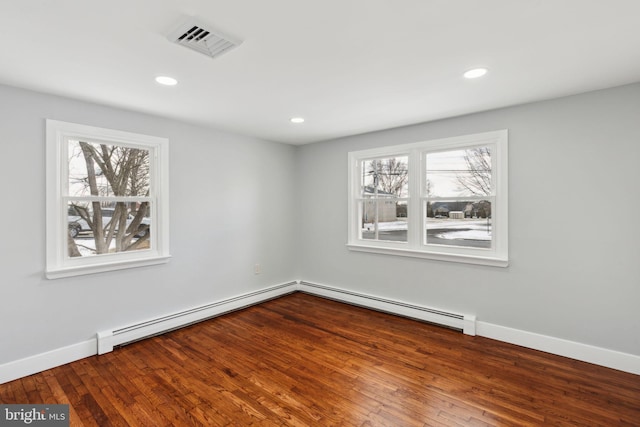 spare room with hardwood / wood-style floors, baseboard heating, and plenty of natural light