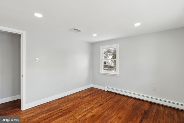 empty room with dark wood-type flooring and a baseboard radiator