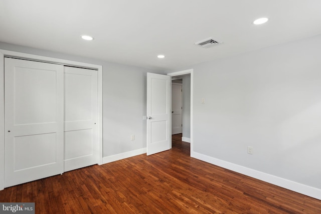 unfurnished bedroom featuring dark hardwood / wood-style floors and a closet