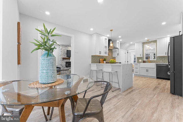 dining space with light hardwood / wood-style floors, a stone fireplace, and sink