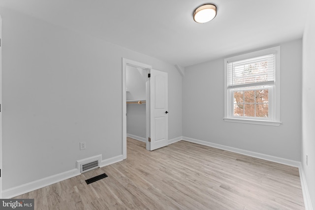 interior space featuring a walk in closet, light hardwood / wood-style floors, and a closet