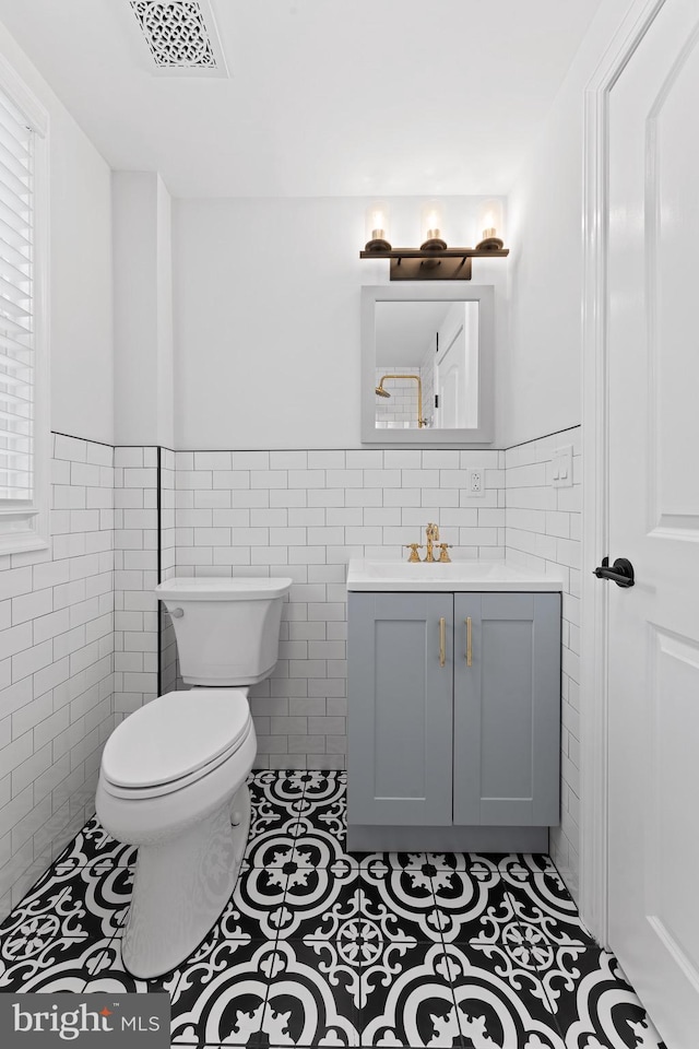 bathroom with tile walls, tile patterned flooring, toilet, and vanity