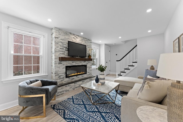 living room with light hardwood / wood-style floors and a stone fireplace