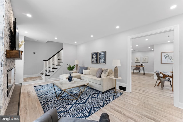 living room with light hardwood / wood-style floors and a stone fireplace