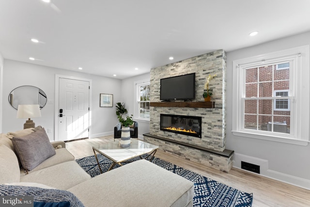 living room featuring a fireplace, a wealth of natural light, and light hardwood / wood-style flooring