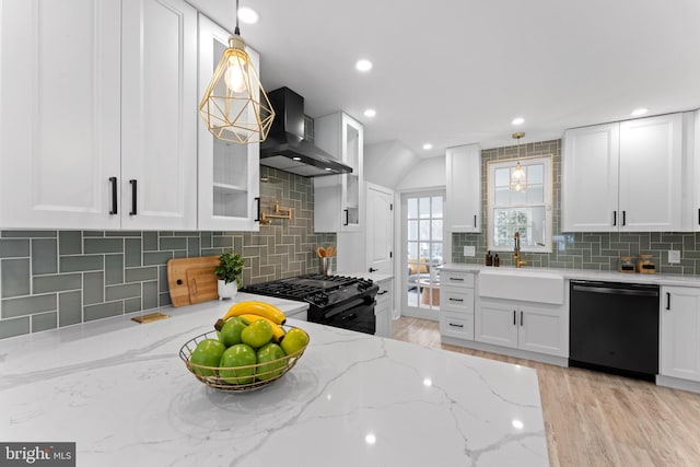 kitchen featuring sink, white cabinetry, black appliances, wall chimney range hood, and pendant lighting