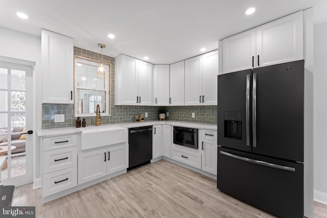 kitchen featuring black appliances, light hardwood / wood-style floors, white cabinets, and sink