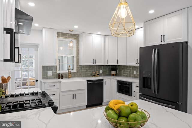 kitchen featuring light stone countertops, pendant lighting, black appliances, white cabinets, and sink