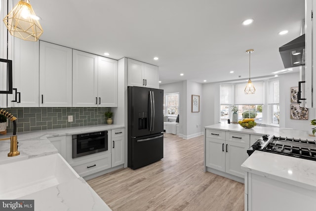 kitchen featuring light stone countertops, black appliances, and white cabinetry