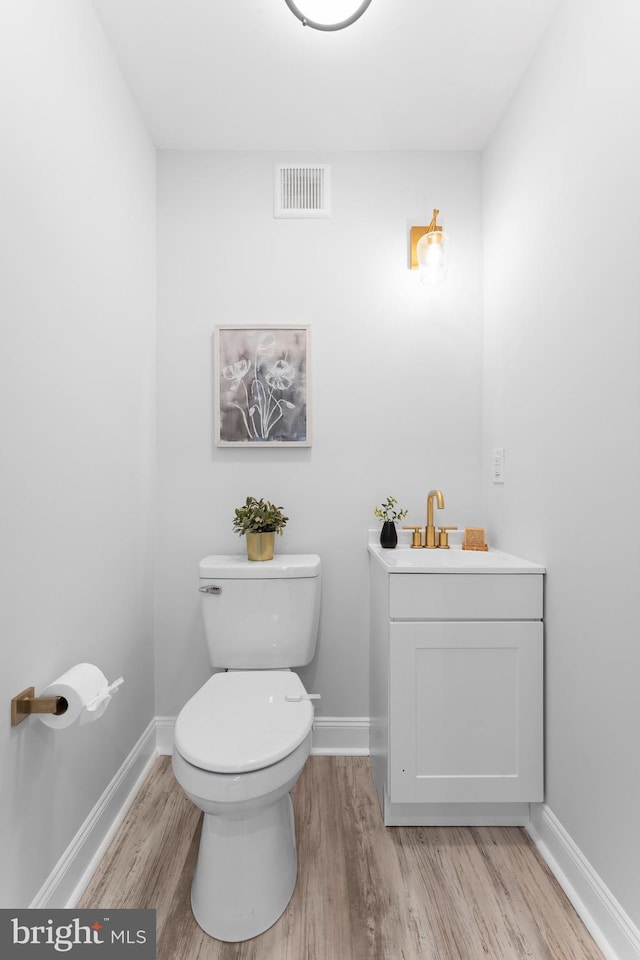 bathroom with toilet, hardwood / wood-style flooring, and vanity