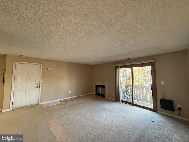 unfurnished living room with a tile fireplace, light carpet, and a textured ceiling