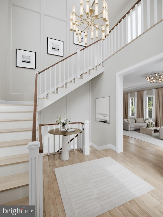 staircase with a notable chandelier, wood-type flooring, and a high ceiling