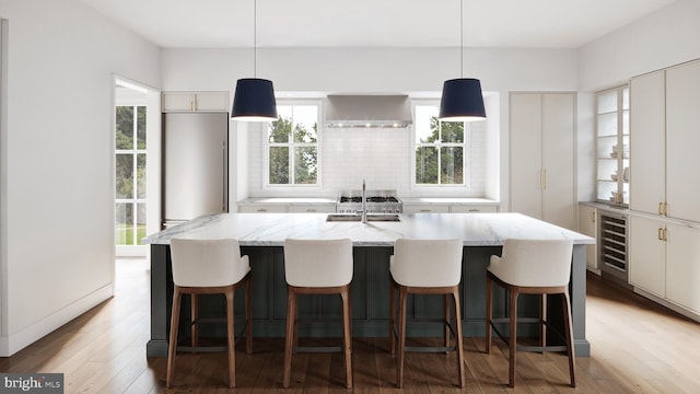 kitchen with sink, beverage cooler, a spacious island, and decorative light fixtures