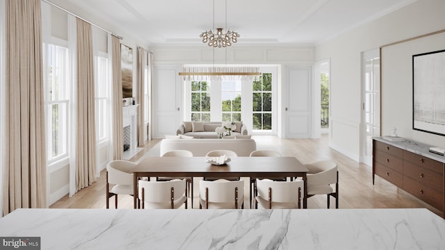 dining area featuring a raised ceiling, light wood-type flooring, an inviting chandelier, and ornamental molding