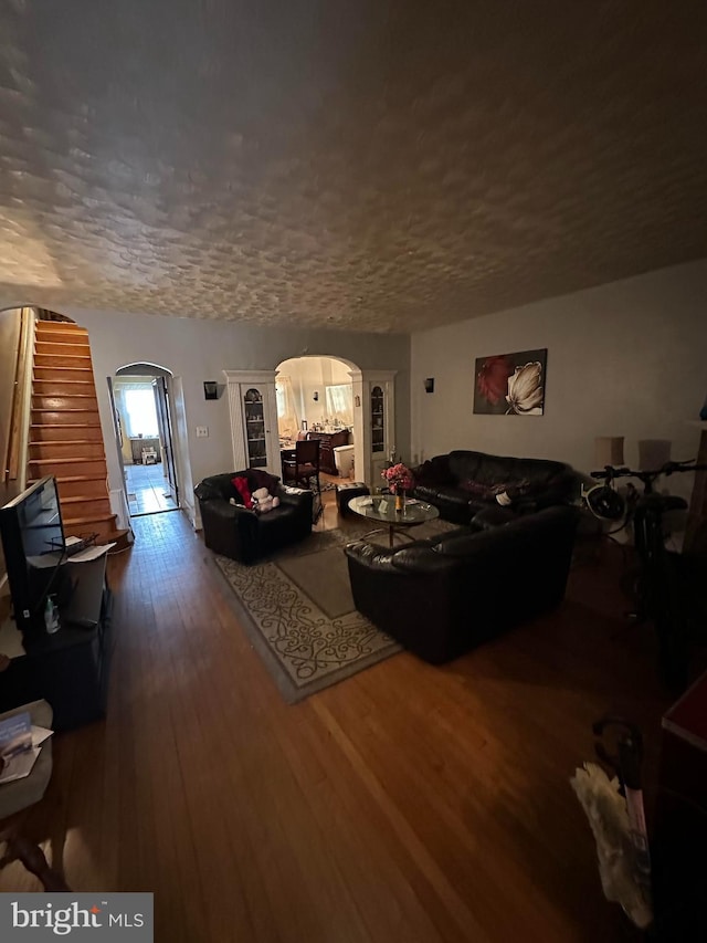 living room with a textured ceiling and dark wood-type flooring