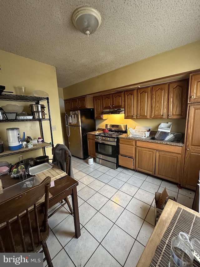 kitchen with light tile patterned floors, stainless steel appliances, and a textured ceiling