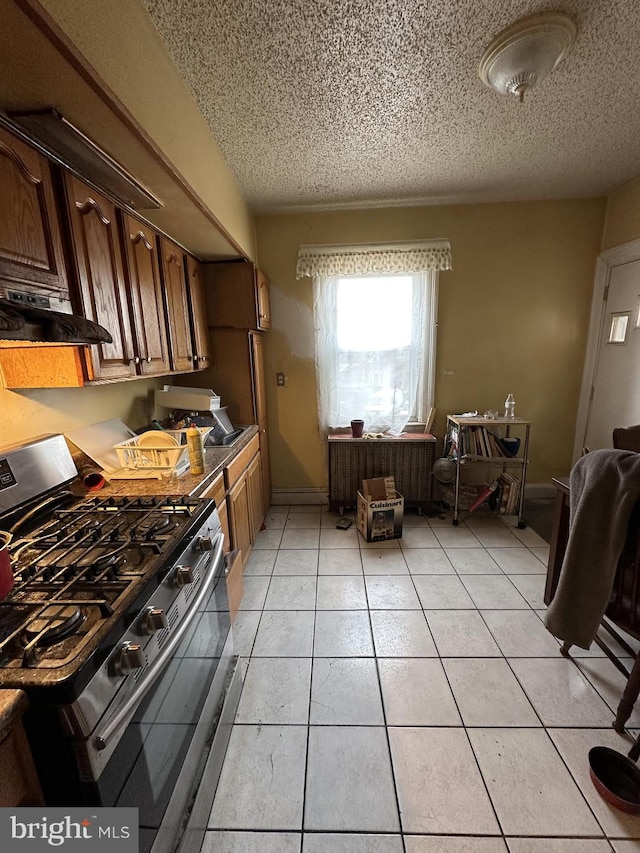 kitchen with stainless steel gas stove, light tile patterned floors, and a textured ceiling