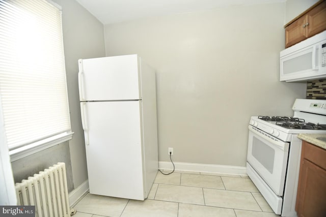 kitchen with radiator, light tile patterned floors, and white appliances