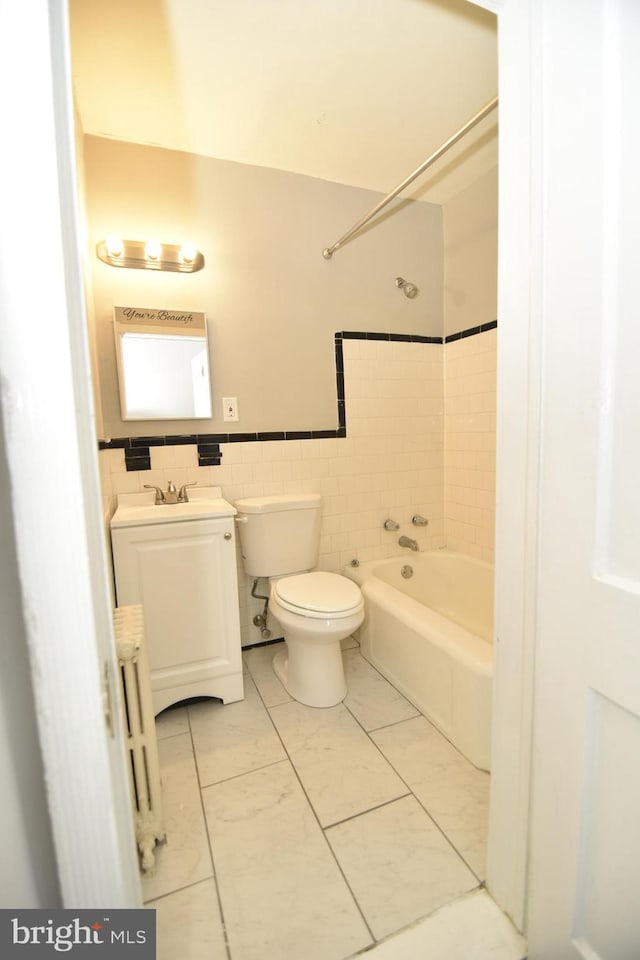 full bathroom with tile patterned floors, vanity, tile walls, radiator heating unit, and toilet