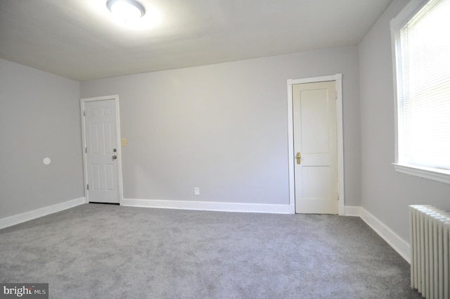 carpeted empty room featuring radiator heating unit