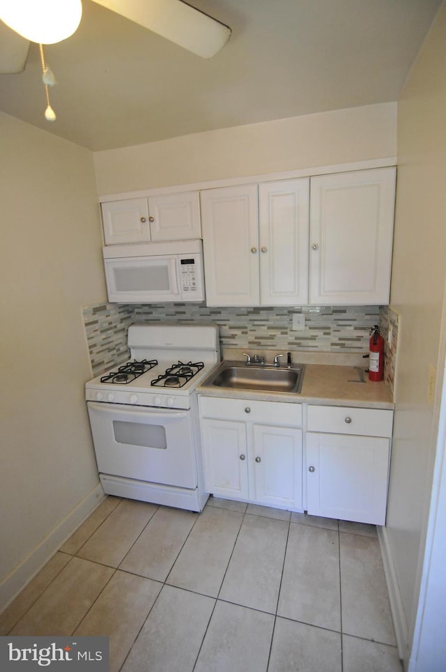 kitchen with tasteful backsplash, white appliances, sink, white cabinets, and light tile patterned flooring