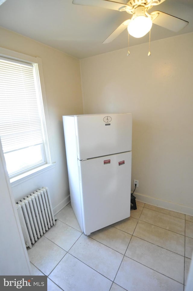 kitchen with ceiling fan, radiator heating unit, white fridge, and light tile patterned flooring