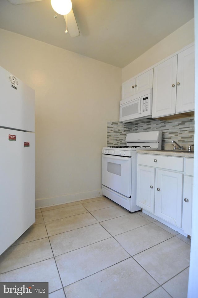 kitchen with decorative backsplash, light tile patterned floors, white appliances, and white cabinetry