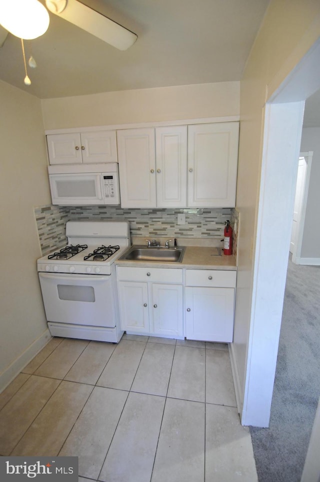 kitchen with sink, light tile patterned floors, backsplash, white appliances, and white cabinets