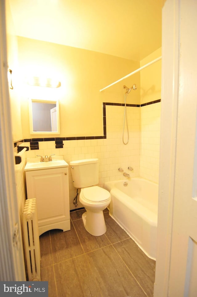 full bathroom with radiator, tile patterned flooring, tiled shower / bath combo, toilet, and tile walls