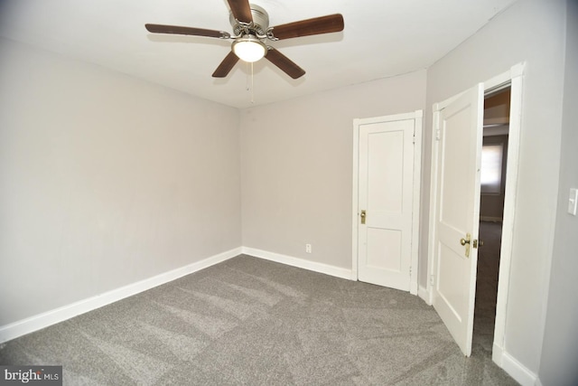 unfurnished room with ceiling fan and dark carpet