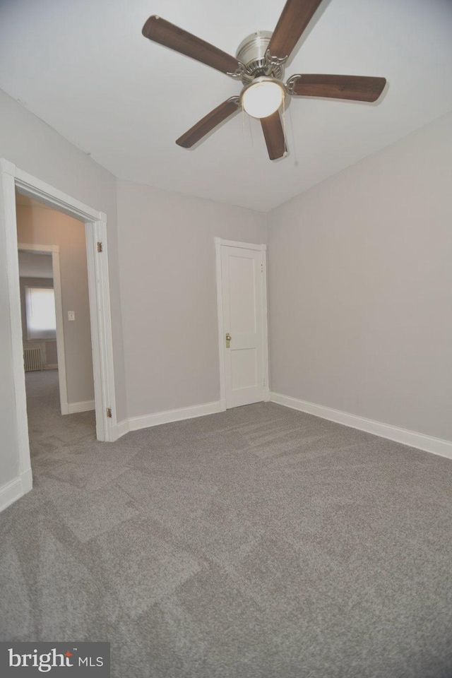 carpeted spare room with ceiling fan and radiator