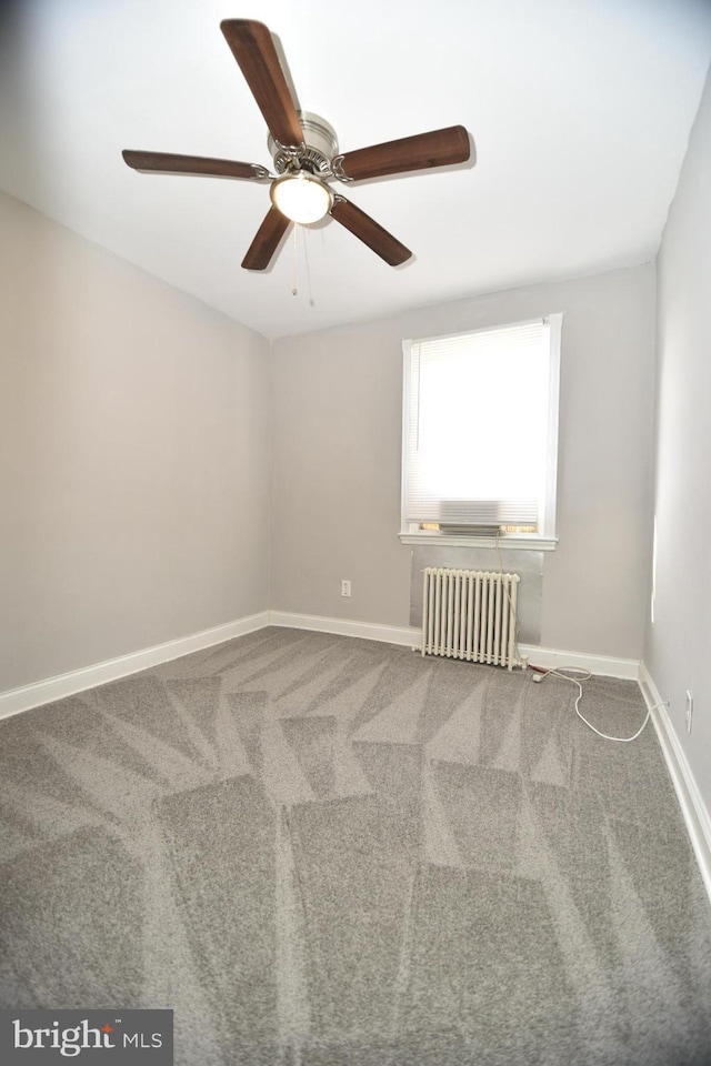 carpeted empty room with radiator and ceiling fan