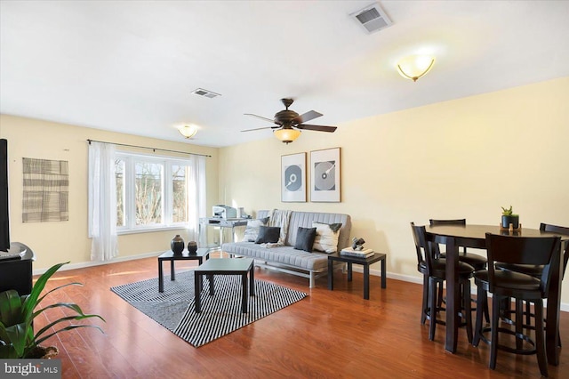 living room featuring ceiling fan and dark wood-type flooring