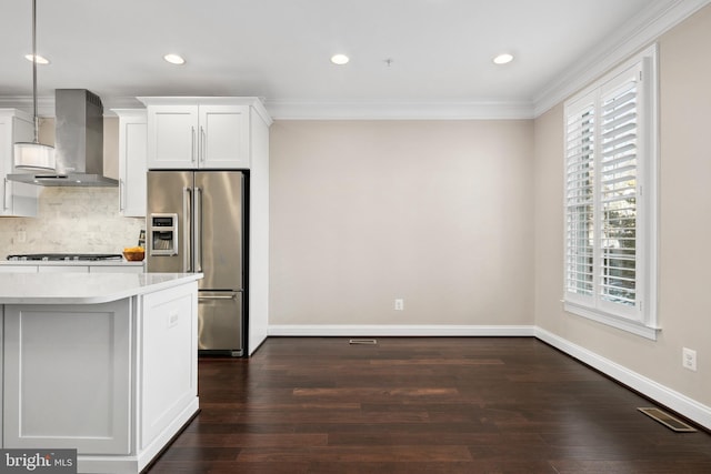 kitchen featuring high end refrigerator, white cabinets, hanging light fixtures, exhaust hood, and gas cooktop