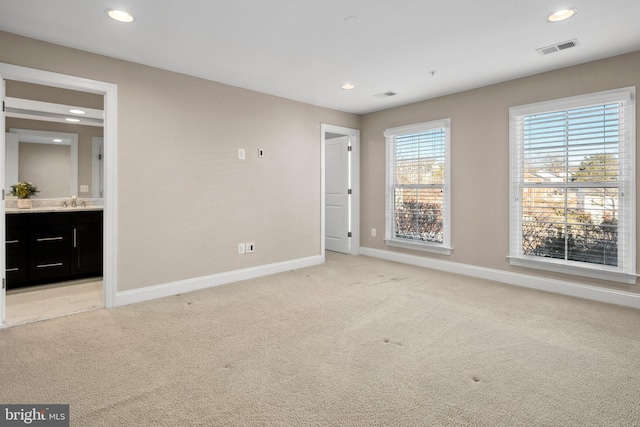 unfurnished bedroom featuring light carpet, sink, and connected bathroom