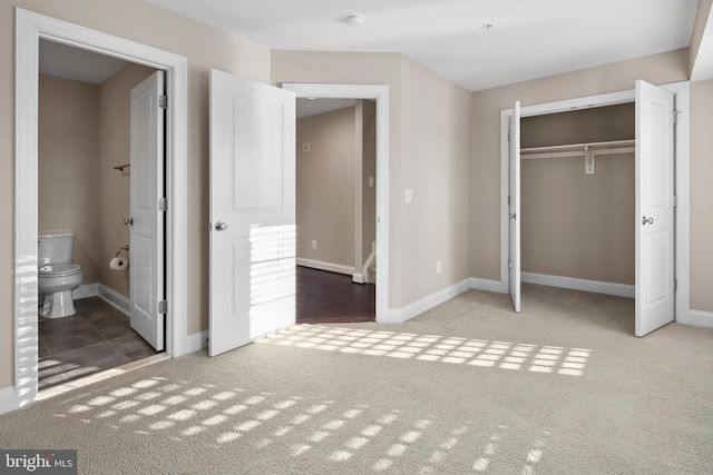 unfurnished bedroom featuring ensuite bath, light colored carpet, and a closet