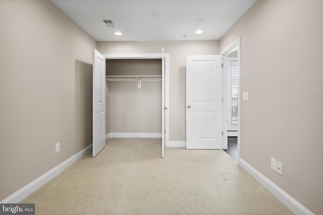 unfurnished bedroom with light colored carpet and a closet