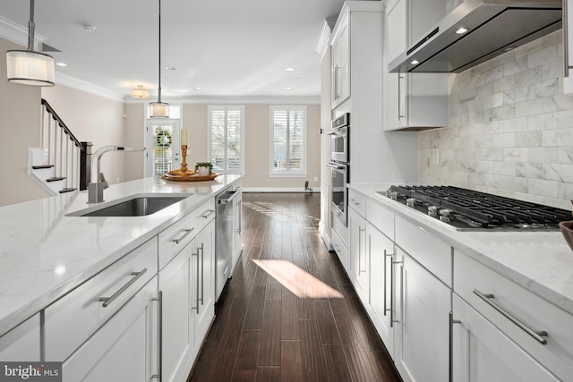 kitchen with wall chimney exhaust hood, decorative light fixtures, backsplash, stainless steel appliances, and white cabinets