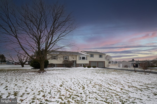 snow covered rear of property featuring a garage