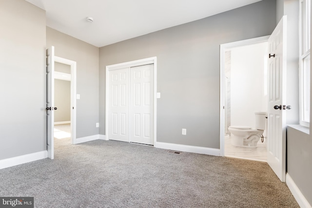 unfurnished bedroom featuring light colored carpet, a closet, and ensuite bathroom