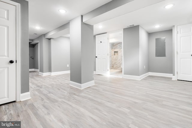 basement with electric panel and light hardwood / wood-style floors