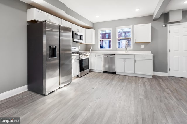 kitchen featuring white cabinets, sink, light wood-type flooring, and stainless steel appliances