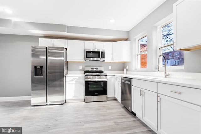 kitchen featuring sink, white cabinets, light wood-type flooring, and appliances with stainless steel finishes