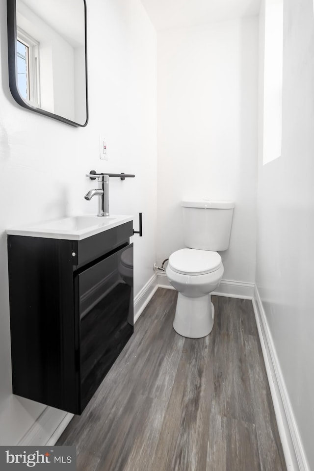 bathroom with wood-type flooring, vanity, and toilet