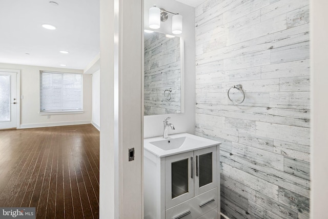 bathroom featuring hardwood / wood-style floors, vanity, and wooden walls