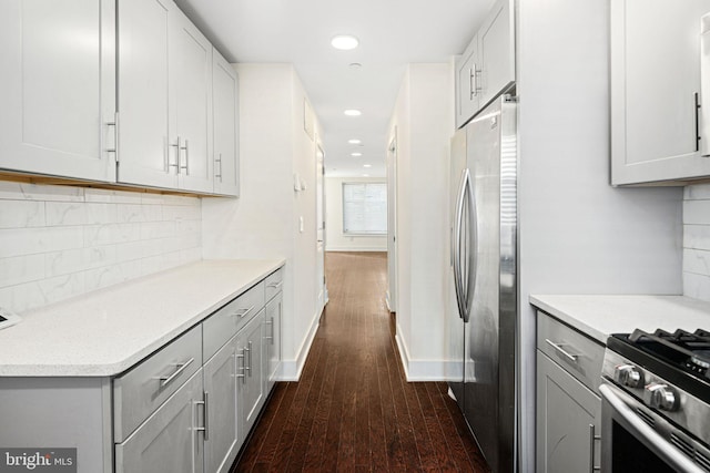 kitchen with dark hardwood / wood-style flooring, white cabinetry, appliances with stainless steel finishes, and tasteful backsplash