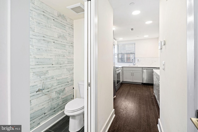 bathroom with wood walls, vanity, wood-type flooring, and toilet