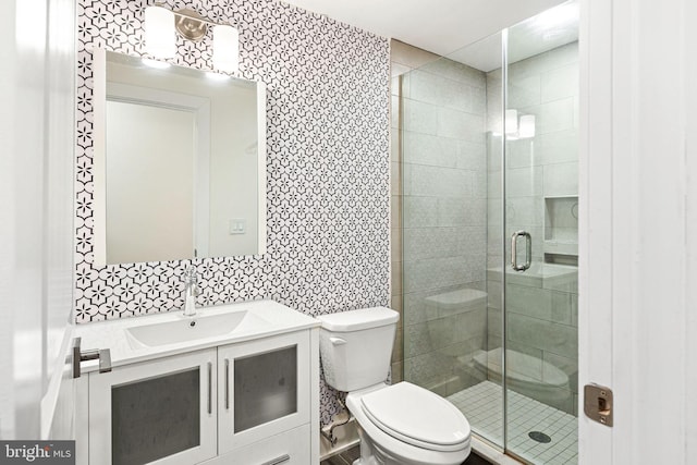 bathroom featuring a shower with door, vanity, and toilet